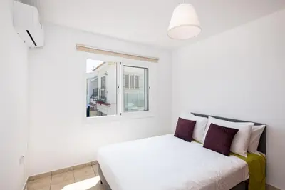 a white bed in a room with a window at Oceanview Apartment in Larnaka