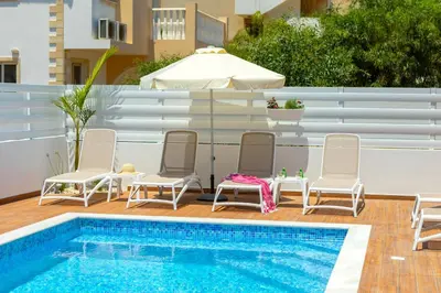 a patio with chairs and a swimming pool at Villa Lantos Central Protaras in Protaras