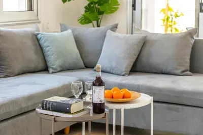a bottle of wine on a table next to a couch at Villa Lantos Central Protaras in Protaras