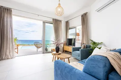 a living room with a blue couch and a view of the ocean at Villa Pacy in Ayios Theodhoros