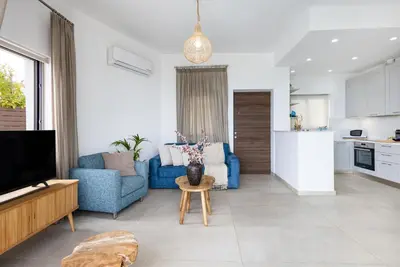 a living room with a blue couch and a kitchen at Villa Pacy in Ayios Theodhoros