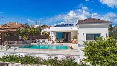 a villa with a swimming pool in front of a house at Villa Pacy in Ayios Theodhoros