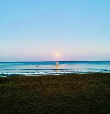 a beach with the sun rising over the ocean at BALI SUITES 404 in Larnaka