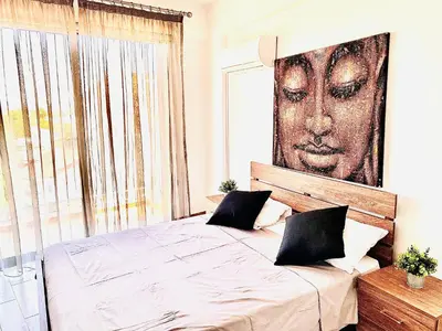 a bedroom with a bed with a large picture on the wall at BALI SUITES 404 in Larnaka