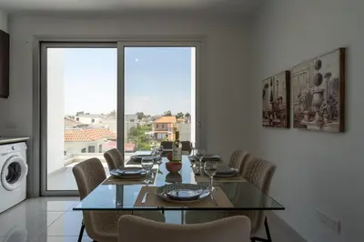 a dining room with a table and chairs and a window at Harmonia 2-BR Apt in Livadia in Larnaka