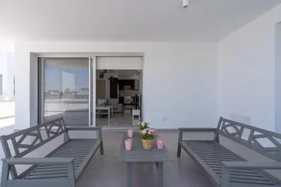 a balcony with two benches and a table with flowers at Harmonia 2-BR Apt in Livadia in Larnaka