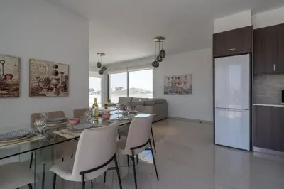 a kitchen and living room with a table and chairs at Harmonia 2-BR Apt in Livadia in Larnaka