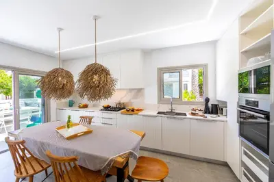 a kitchen with a table and chairs and a kitchen with white cabinets at Protaras Rose By The Sea Villa in Protaras