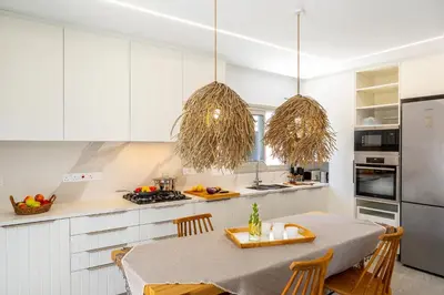 a kitchen with white cabinets and a table with chairs at Protaras Rose By The Sea Villa in Protaras