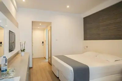 a white bedroom with a bed and a table at MARGADINA HOTEL in Ayia Napa