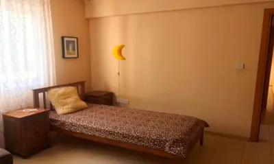 a bedroom with a bed and a lamp and a window at 2 bedroom with private garden, walk to Nissi Beach, communal swimming pool in Ayia Napa