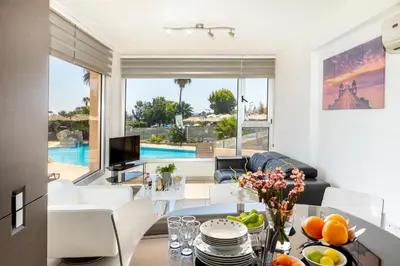 a living room with a view of a pool at Fig Tree bay Apartment 103 in Protaras