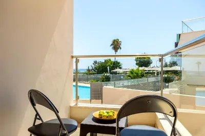 a balcony with two chairs and a bowl of fruit on a table at Fig Tree bay Apartment 103 in Protaras