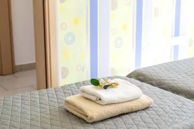 a towel with a flower on top of a bed at Fig Tree bay Apartment 103 in Protaras