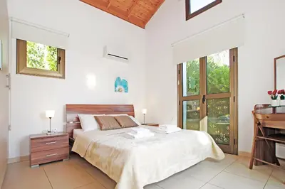 a white bedroom with a bed and a piano at Villa Louisa in Ayia Napa
