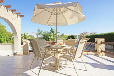 a table and chairs with an umbrella on a patio at Villa Louisa in Ayia Napa