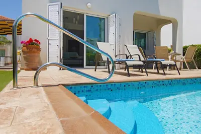 a swimming pool with a hand rail next to a house at Villa Palm in Protaras