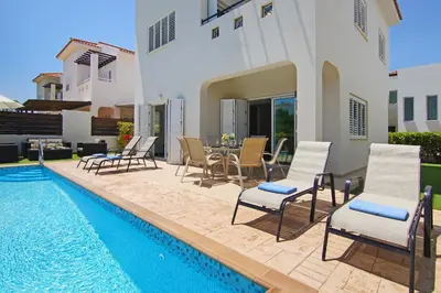 a villa with a pool and chairs and a table at Villa Palm in Protaras