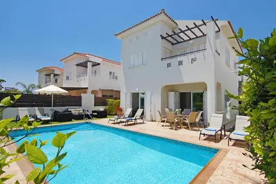a villa with a swimming pool in front of a house at Villa Palm in Protaras