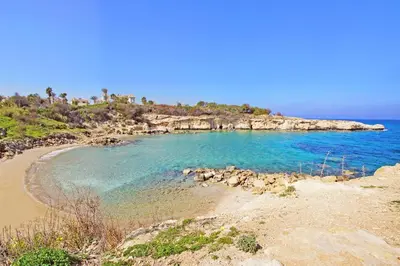 a beach with blue water and a rocky island at Villa Palm in Protaras