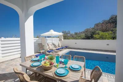 a dining table with chairs next to a swimming pool at Romeo & Juliet in Protaras