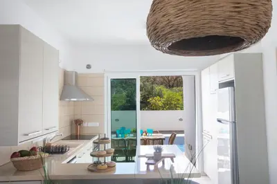 a kitchen with white cabinets and a large window at Romeo & Juliet in Protaras