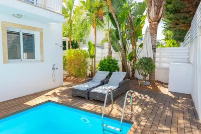 a patio with a pool and a couch and a house at Protaras Villa Dafni in Protaras