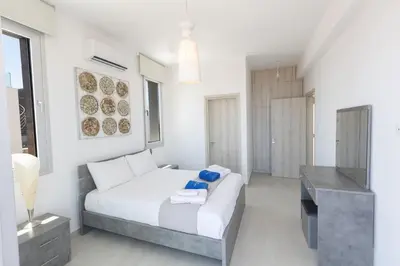 a white bedroom with a bed and a television at Sol E Mar Villas ( Gold Emerging Villas ) in Protaras