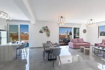 a living room and kitchen with a pink couch at Sol E Mar Villas ( Gold Emerging Villas ) in Protaras