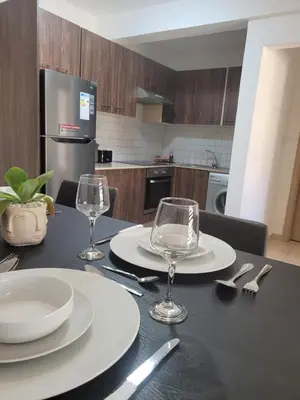 a table with two plates and wine glasses on it at Cielo Apartment in Ayia Napa