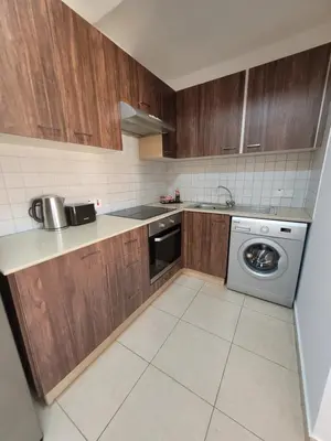 a kitchen with wooden cabinets and a washing machine at Cielo Apartment in Ayia Napa