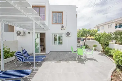 a white house with chairs and a patio at Merab Holidays Apartment Castalia 62 in Ayia Napa