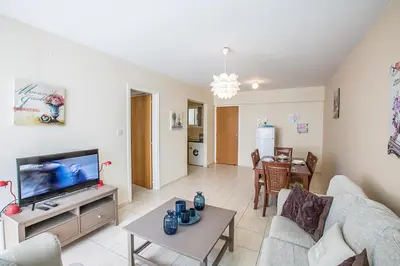 a living room with a couch and a tv and a table at Merab Holidays Apartment Castalia 62 in Ayia Napa
