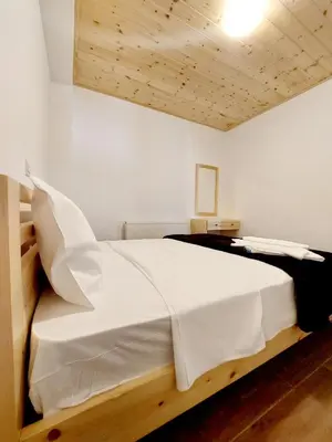 a bedroom with a large white bed with a wooden headboard at Agros Green Valley Suites in Limassol