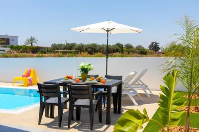 a black table with chairs and an umbrella next to a pool at Alasia Villas in Paralimni
