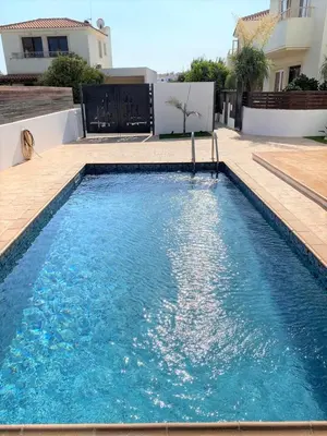 a swimming pool with blue water in front of a house at Orestiada Villa Ekaterina 3 bdrm in Protaras
