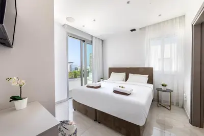 a white bedroom with a large bed and a window at Villa Green Haven 2 Protaras Cyprus in Protaras