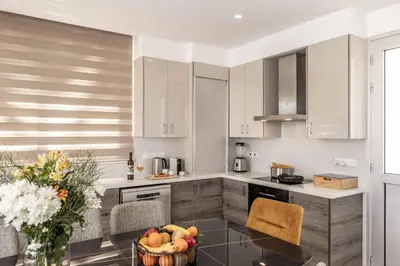 a kitchen with white cabinets and a table with a bowl of fruit at Villa Green Haven 2 Protaras Cyprus in Protaras