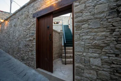 a wooden door in a stone wall with a staircase at Eidyllio Luxury Suites Omodos in Omodos