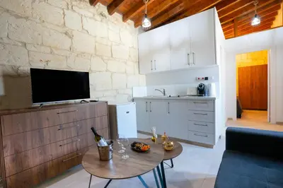 a kitchen and living room with a table and a tv at Eidyllio Luxury Suites Omodos in Omodos