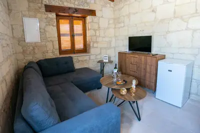 a living room with a couch and a tv and a table at Eidyllio Luxury Suites Omodos in Omodos