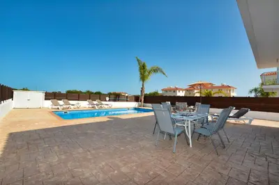 a patio with a table and chairs next to a pool at Nissi Villa Ourania in Ayia Napa