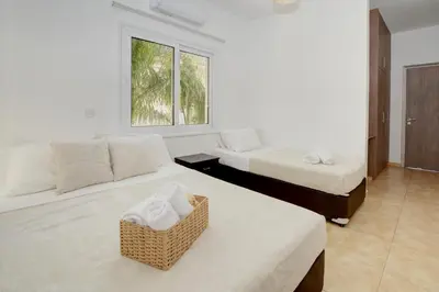 a white room with two beds and a couch at Nissi Villa Ourania in Ayia Napa