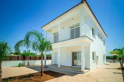 a white house with a palm tree in front of it at Nissi Villa Ourania in Ayia Napa