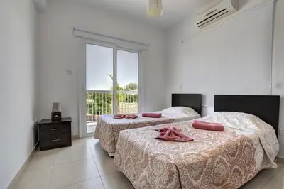 two beds in a white room with a window at Nissi Villa Ourania in Ayia Napa
