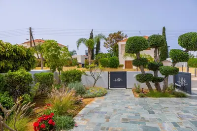 a garden with a stone walkway in front of a house at Green Heaven Villa 3 in Protaras