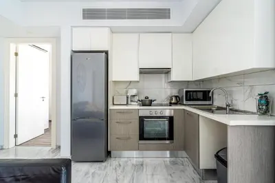 a kitchen with white cabinets and a stainless steel refrigerator at Oyster 1-BR Apt in Larnaca in Larnaka