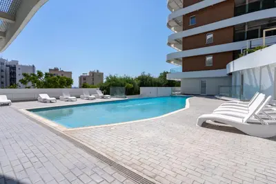 a swimming pool with lounge chairs and a building at Oyster 1-BR Apt in Larnaca in Larnaka