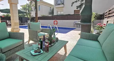a patio with a table and chairs and a pool at GREAT VILLA MARIA in Paralimni