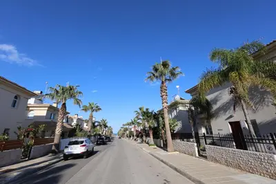 a street with palm trees and a car parked on the road at GREAT VILLA MARIA in Paralimni